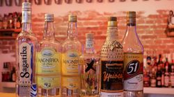 Ein Mann hält eine Flasche Cachaca und lächelt