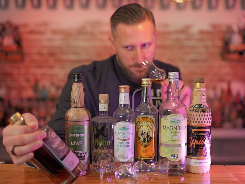 Ein Mann hält eine Flasche Cachaca und lächelt