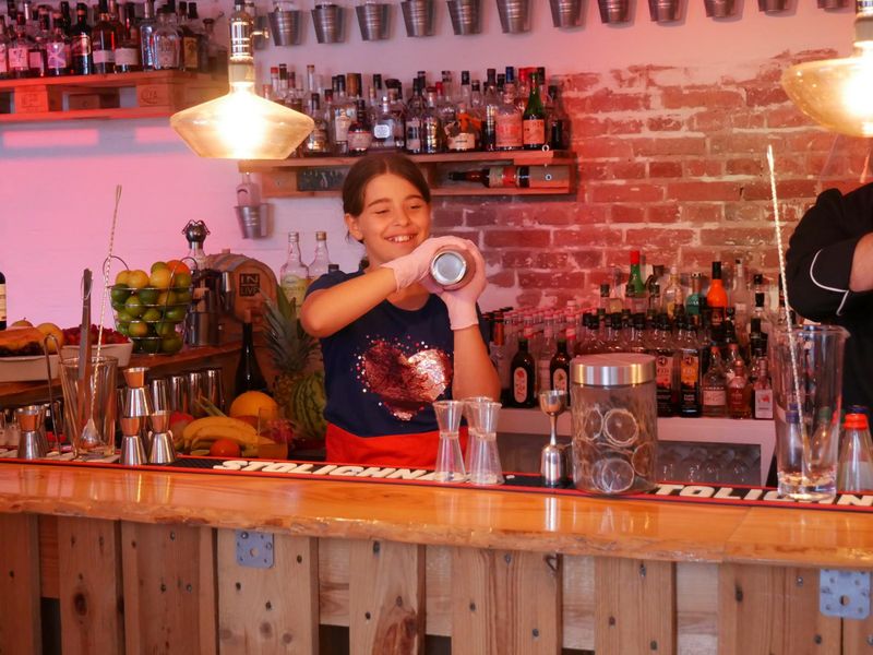 Teilnehmer bei dem Family Cocktailworkshop mixen hinter der Bar Cocktails