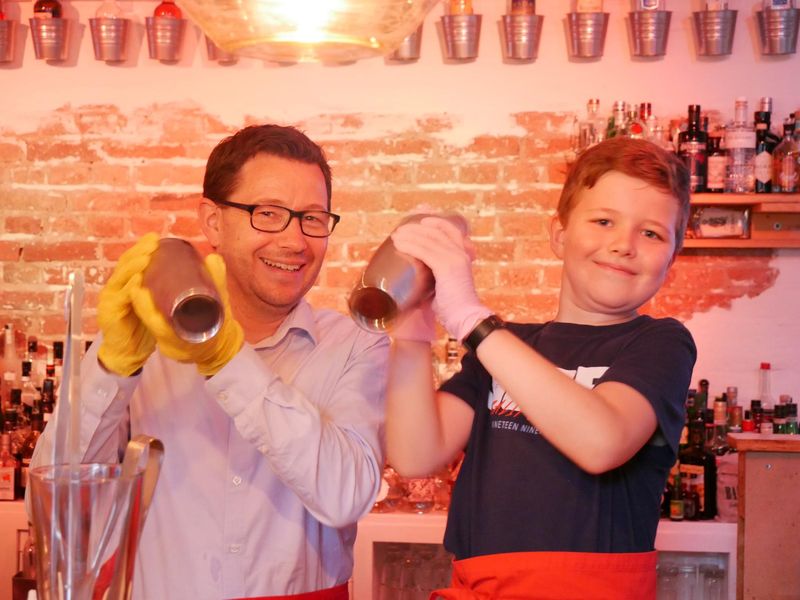 Teilnehmer bei dem Family Cocktailworkshop mixen hinter der Bar Cocktails