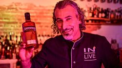 Ein Mann hält eine Flasche Gin und lächelt