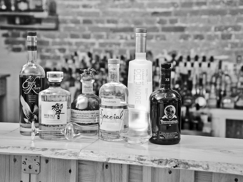 Mehrere Whisky-Flaschen stehen aufgereiht auf einer Bar