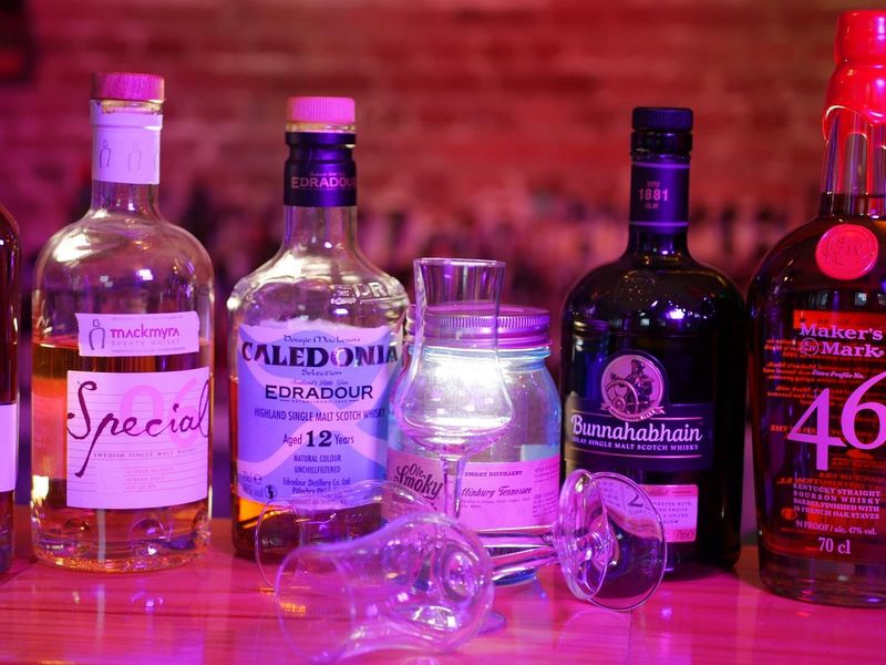 Mehrere Whisky-Flaschen stehen aufgereiht auf einer Bar