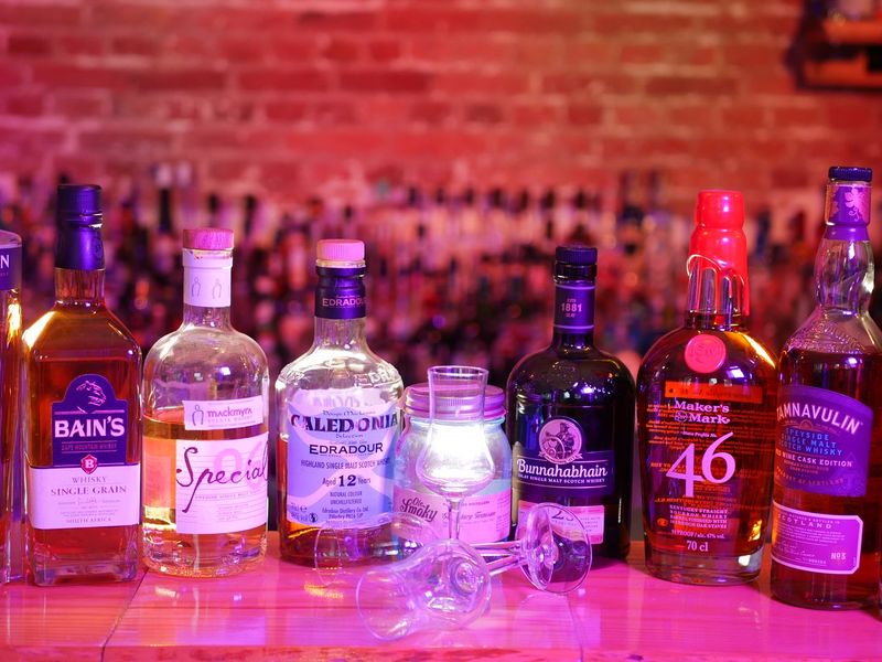 Mehrere Whisky-Flaschen stehen aufgereiht auf einer Bar